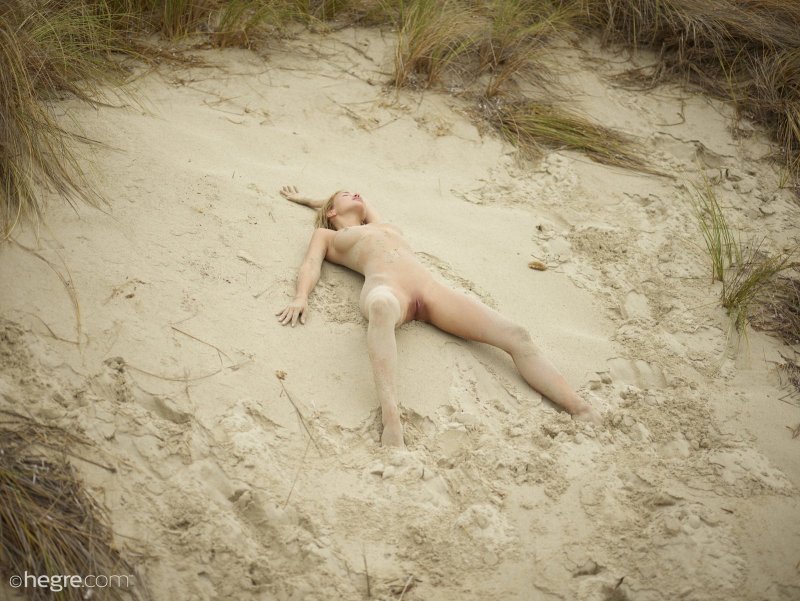 Голая красотка измазанная в песке позирует на пляже - фото